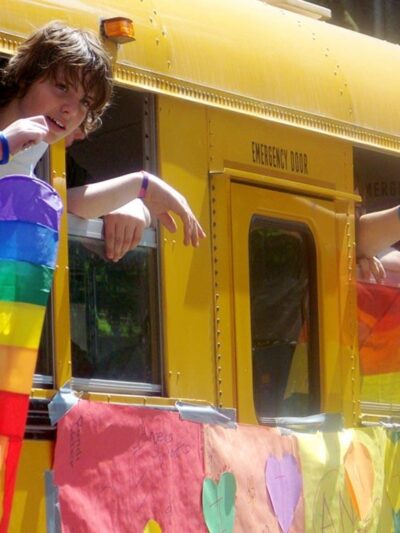 Students on a school bus waving LGBT flags