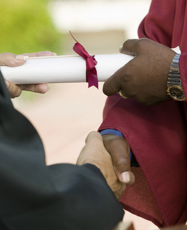 A black man receiving his diploma and giving a handshake.