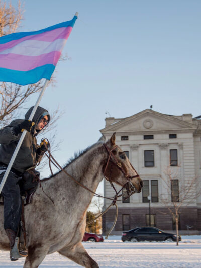 Image of a person riding a horse holding a Trans flag