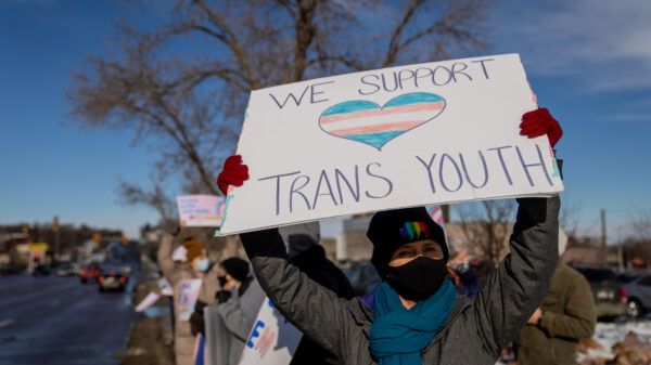 Person with a sign that reads "we support trans youth"