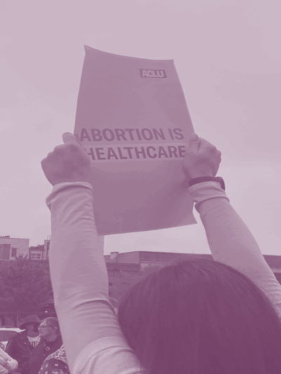 A person holding an "Abortion is healthcare" protest poster