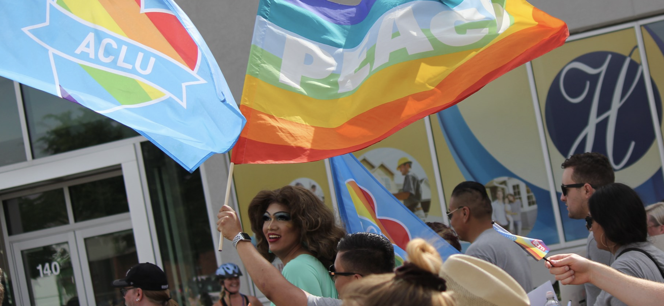 Image of two pride flags and a crowd at a parade