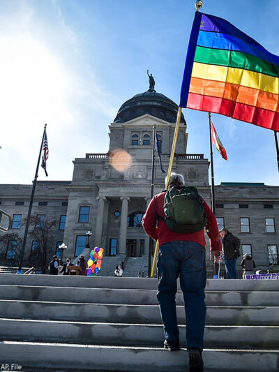 Person walking up stairs with a rainbow flag