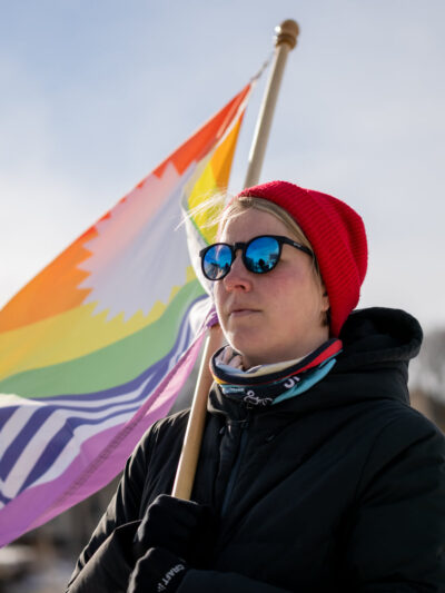 Person holding a pride flag, looking onward.