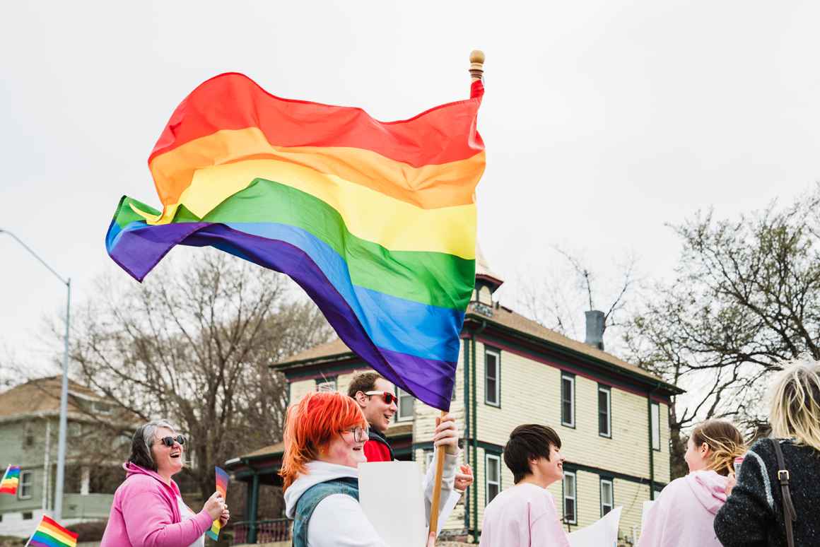 person holding a rainbow flag at a rally