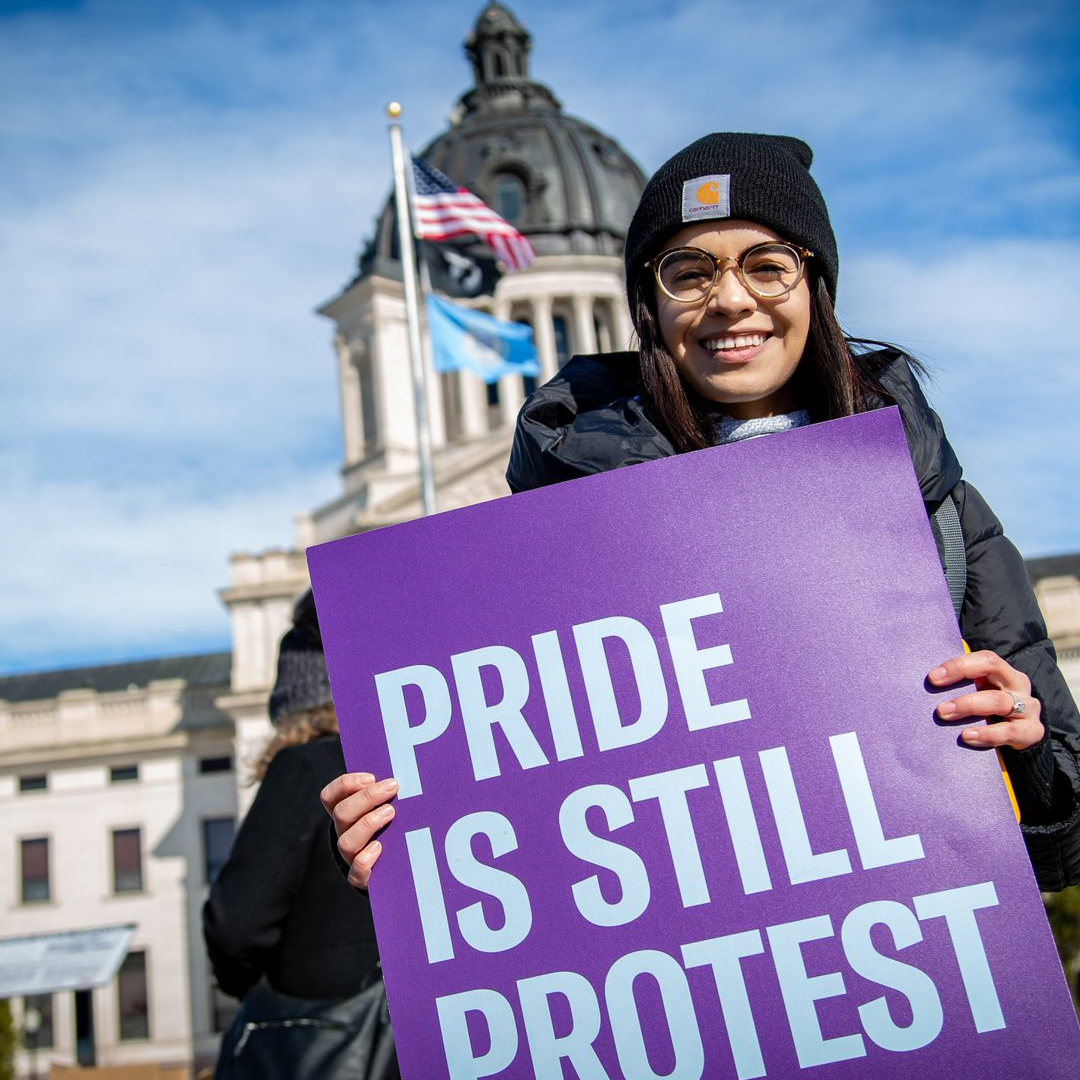 Angelica holding a "Pride is Still Protest" sign