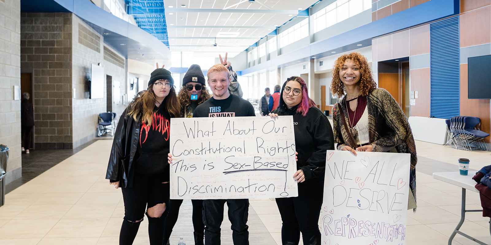 People at a Legislative Coffee holding protest signs 