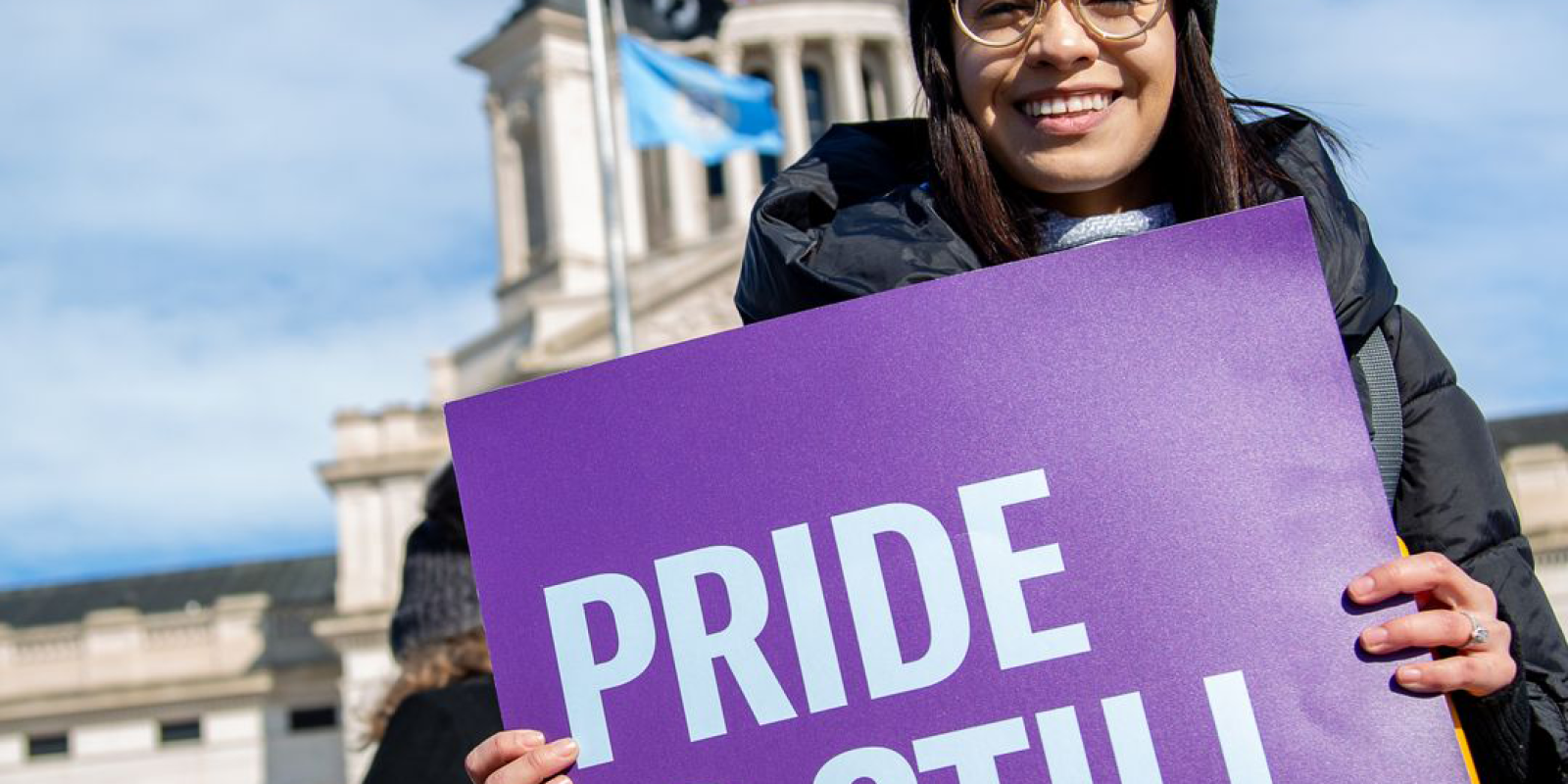 Angelica holding a "Pride is Still Protest" sign