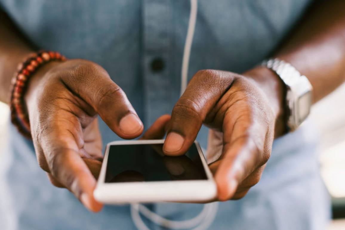 Person holding a phone on a pink background