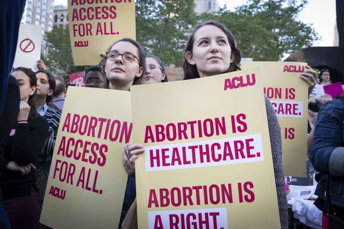 Image of peple holding signs that read, "Abortion is healthcare. Abortion is a right."