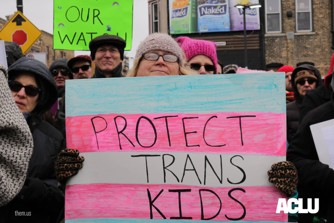 photo of a woman with a protect trans kids poster