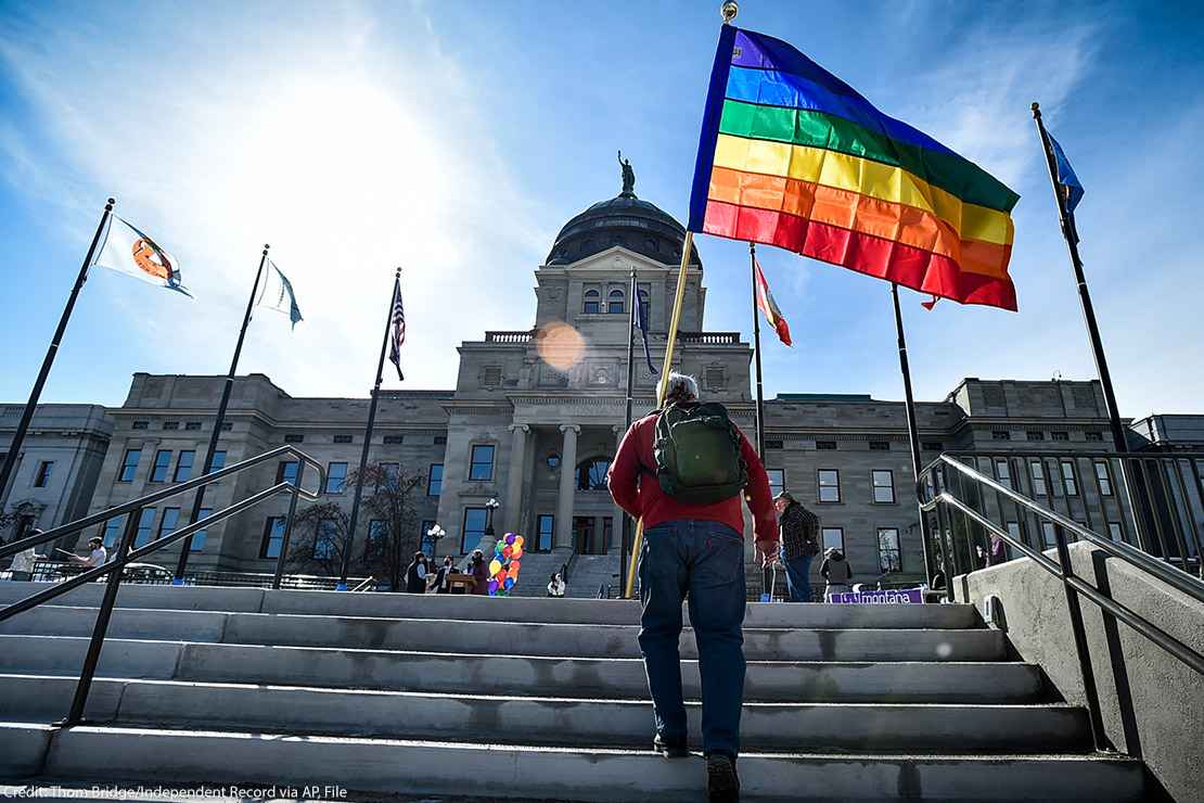 Person walking up stairs with a rainbow flag