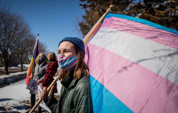 Image of someone holding a trans flag