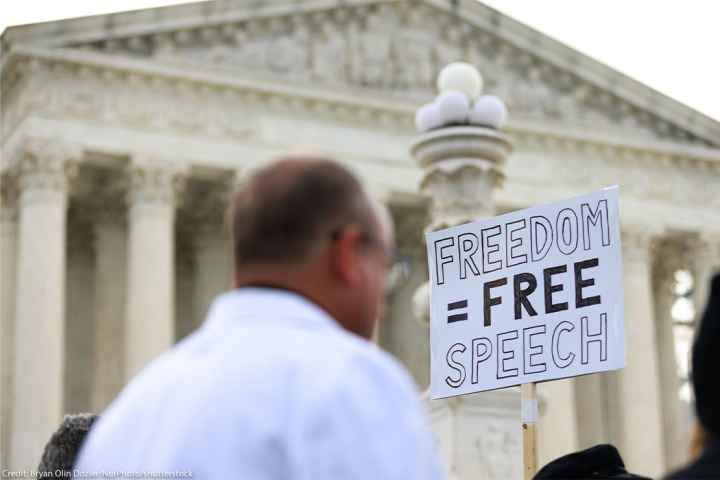 Free Speech supporters hold up a sign reading "FREEDOM = FREE SPEECH" outside the U.S. Supreme Court.