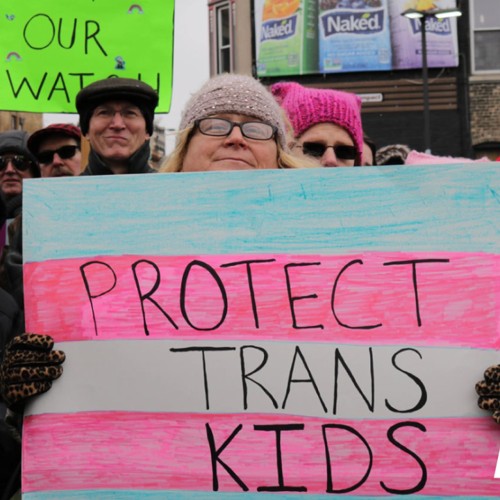 photo of a woman with a protect trans kids poster