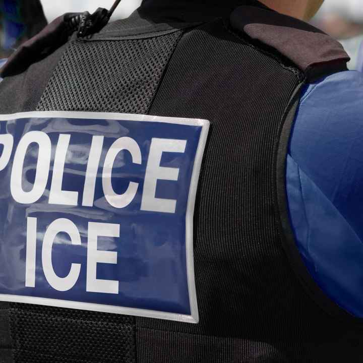 Close-up of POLICE ICE marking on the back of a stab proof vest uniform worn by a police officer.